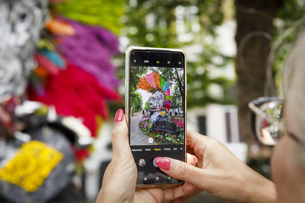 someone taking a photo with their phone of a mohawk-ed flower sculpture
