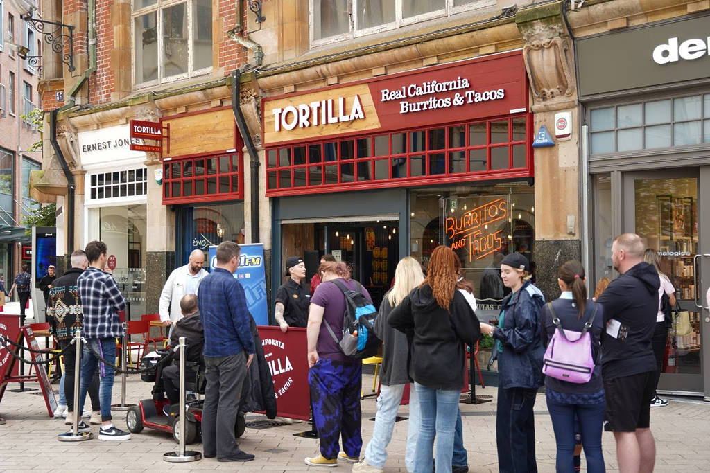 people lining up for free burritos outside a tortilla restaurant