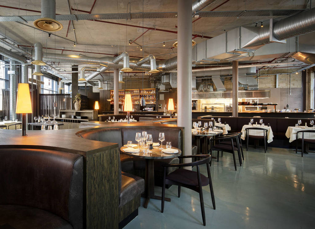 the interior of ibai restaurant with cosy booth seating, smaller tables for two, and a rustic exposed ceiling interior