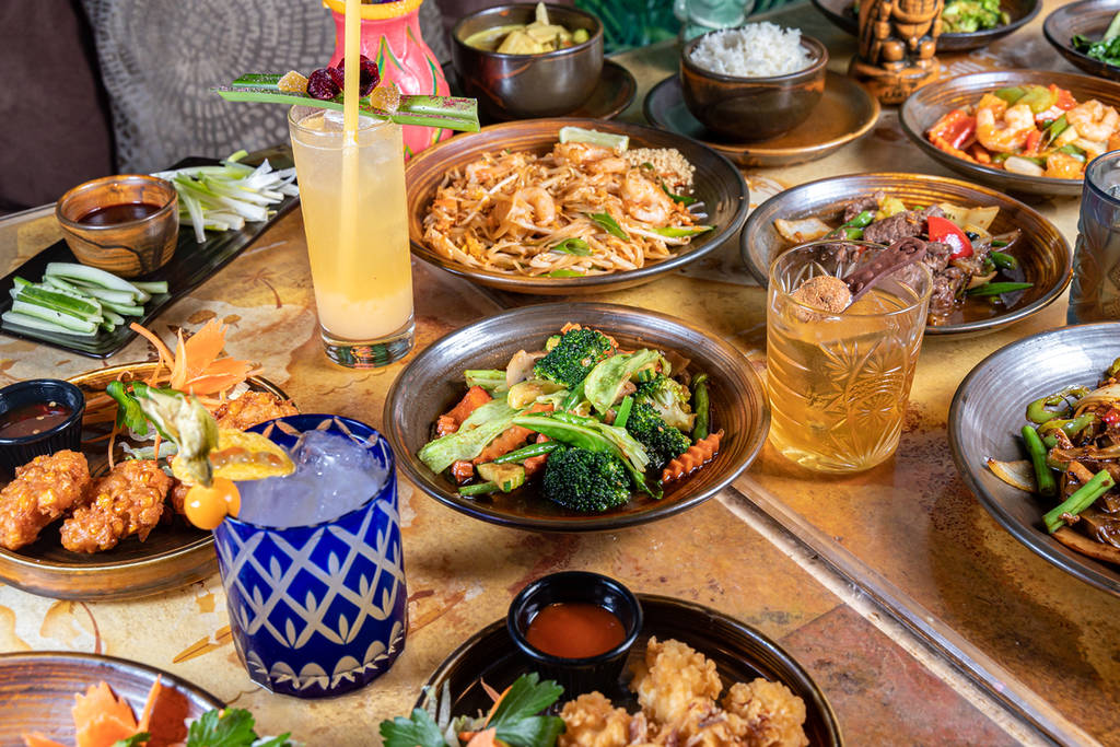 un assortimento di cocktail tropicali e piatti di ispirazione thailandese su un tavolo