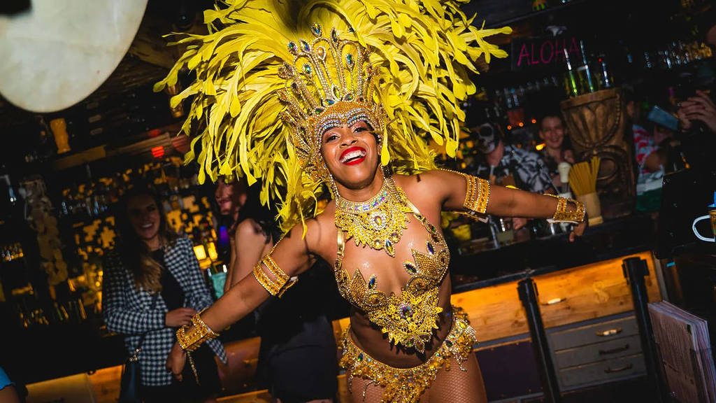 una ballerina in un costume in stile carnevalesco con un elaborato copricapo piumato