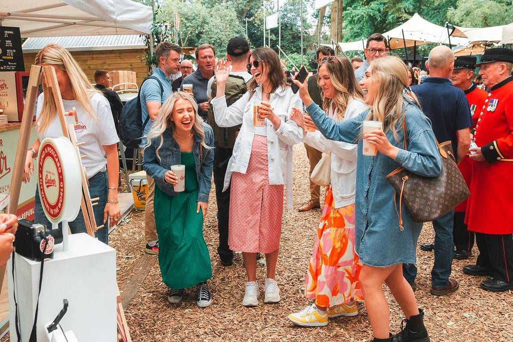 a group of friends at the savour food and drink festival laughing and having a good time as they sample drinks