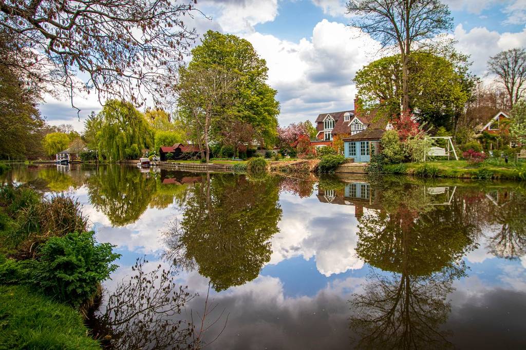 Blick auf Häuser und Boote, die sich im Fluss Wey in Weybridge spiegeln