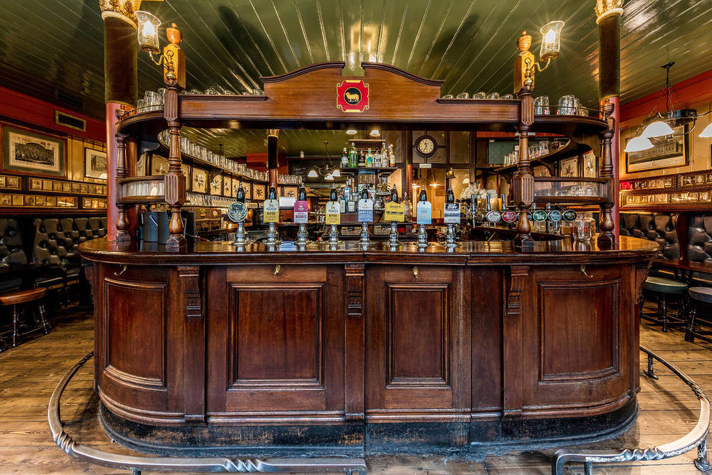 un bar de estilo clásico con fachada de madera en un pub con una exposición de grifos de cerveza de barril que ofrecen una gran variedad de cervezas