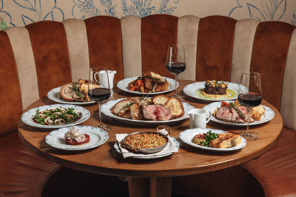 una enorme mesa cubierta con un impresionante surtido de asados dominicales compuesto por innumerables platos de comida sustanciosa