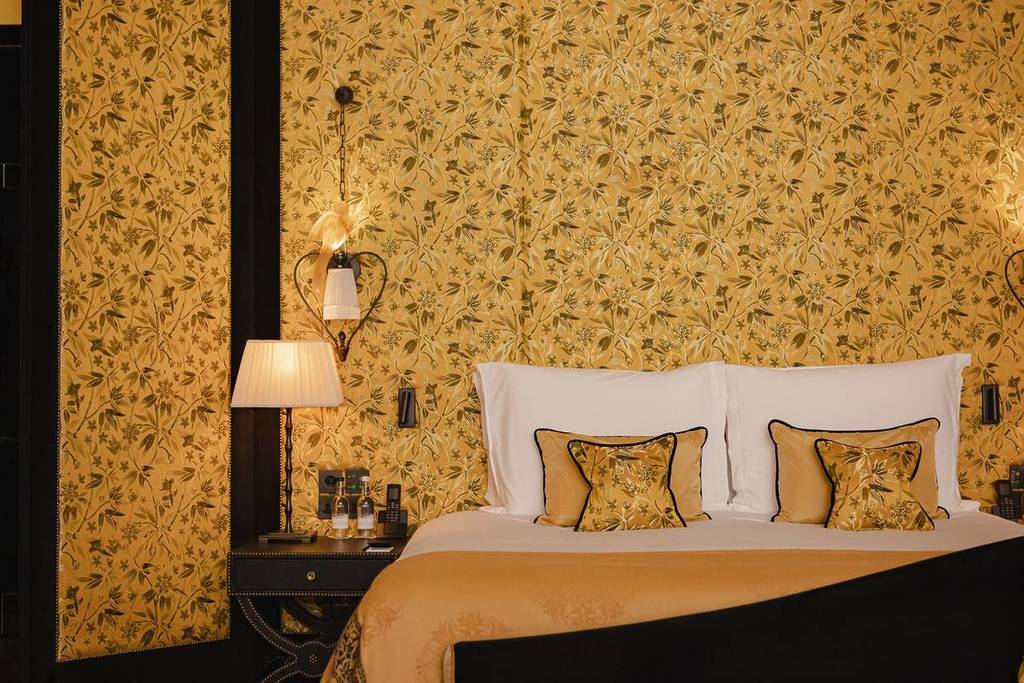 Een gouden muur met een bed ervoor en gouden kussens.
