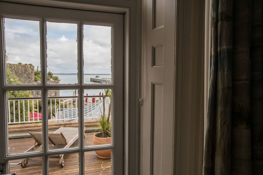 Uma janela que dá para uma varanda com vista para o mar