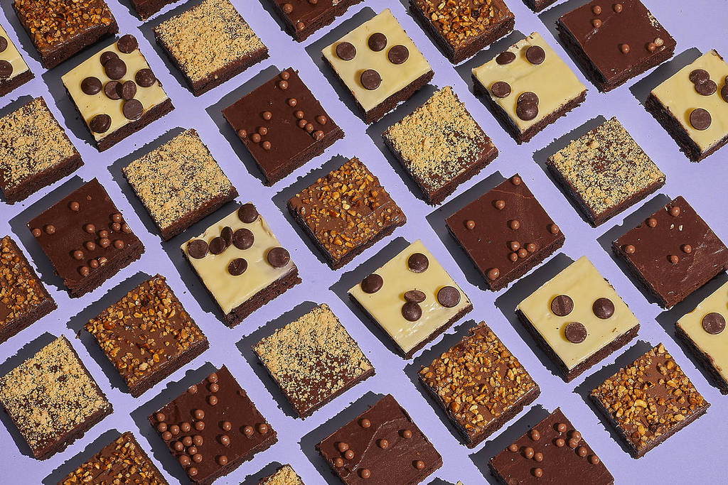 una variedad de brownies diferentes presentados sobre un fondo morado, que resalta los intensos tonos marrones del chocolate