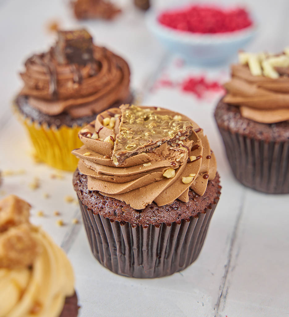 un trío de cupcakes con glaseado de chocolate y virutas de colores