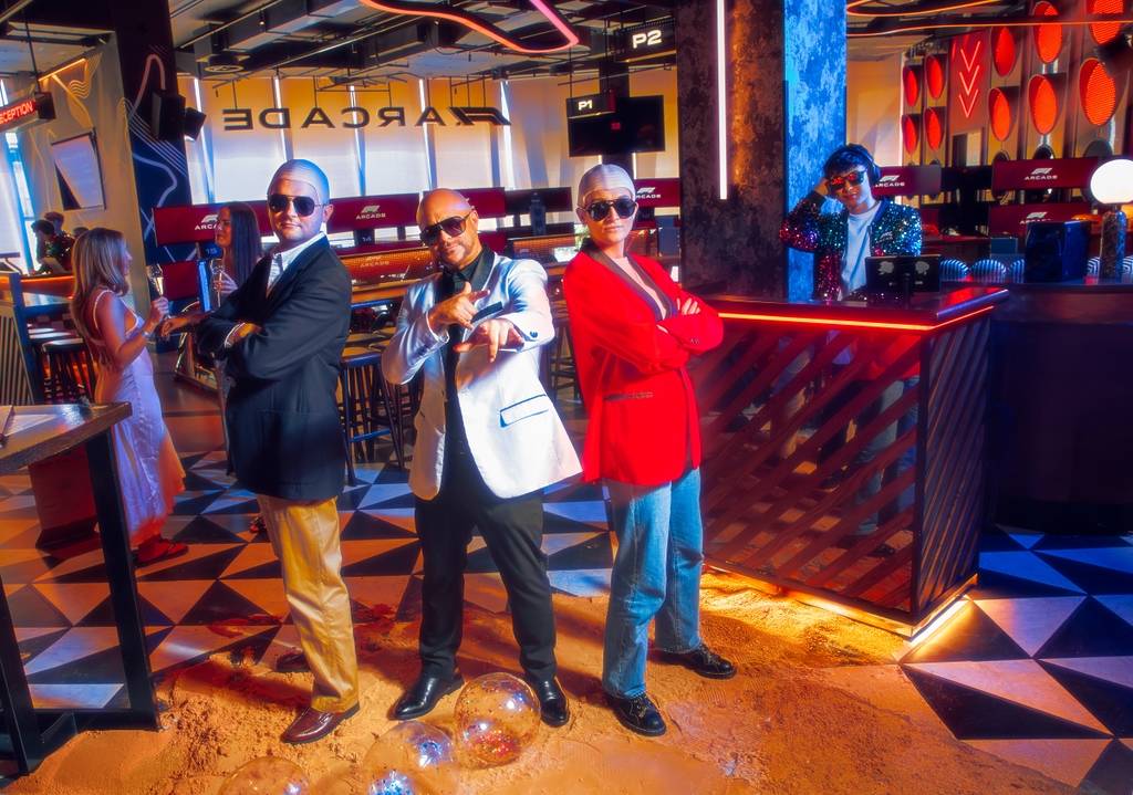 Group of three standing up dressed as Pitbull at a venue in London