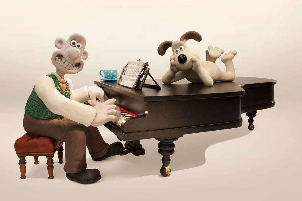 Wallace und Gromit sitzen und liegen auf einem Klavier