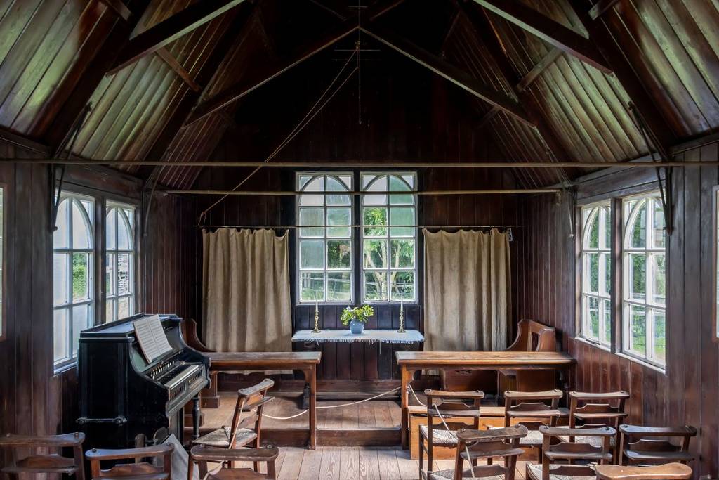 L'intérieur d'un bâtiment historique avec des tables, des bureaux et un piano
