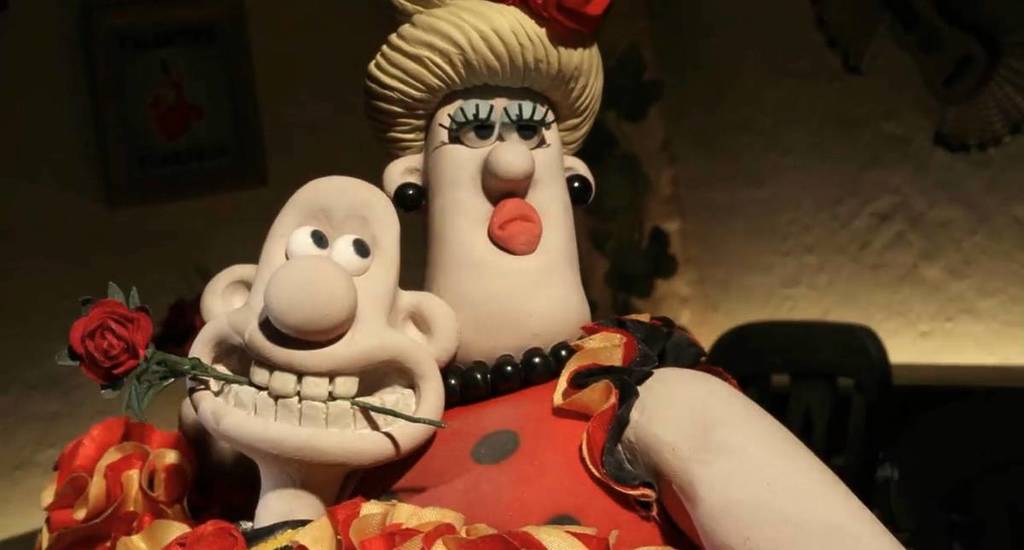 Ein Standbild aus einem Wallace-und-Gromit-Film, das Wallace zeigt, wie er mit jemandem tanzt, während er eine Rose zwischen den Zähnen hält