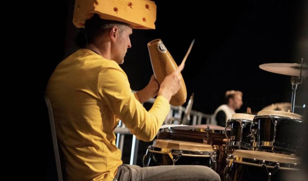 ein Schlagzeuger, der in einem Orchester spielt, während er als Käseblock verkleidet ist
