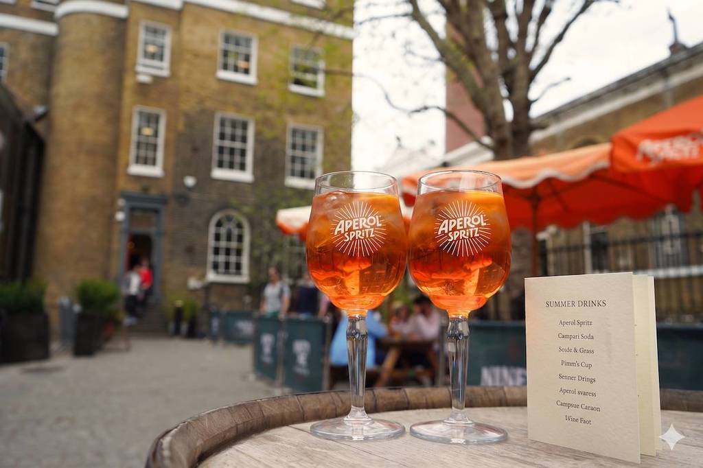 two aperol spritz glasses on a barrel in a courtyard