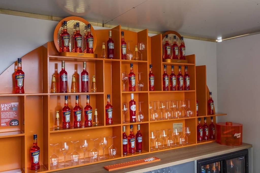 an orange wall with aperol bottles and glasses