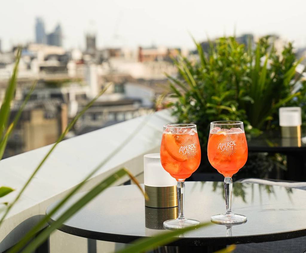 two aperol spritz on a table on a rooftop terrace