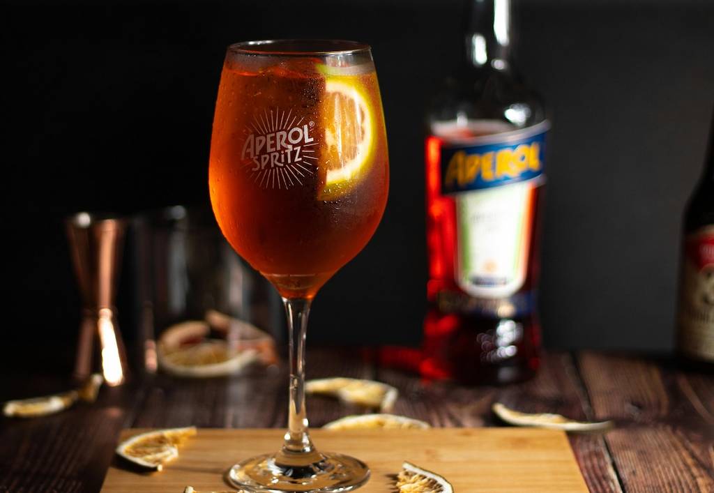 aperol spritz on a wooden chopping board in front of an aperol bottle