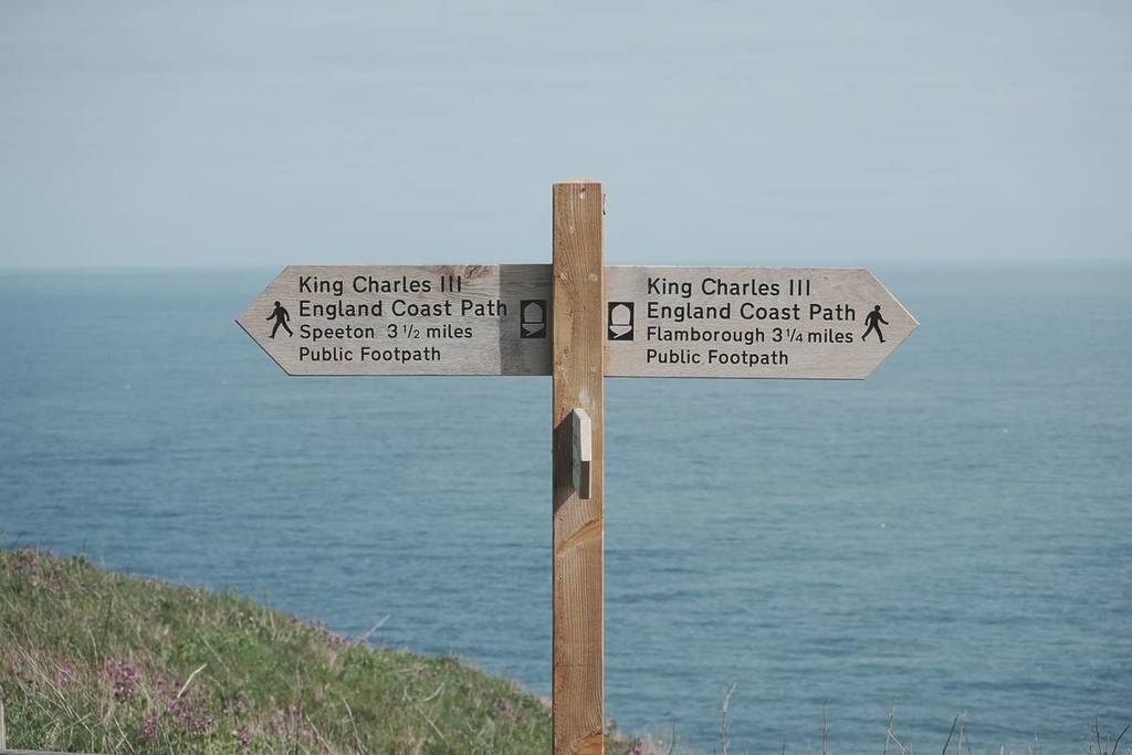 signage pointing towards the coastal walking route with the sea in the background