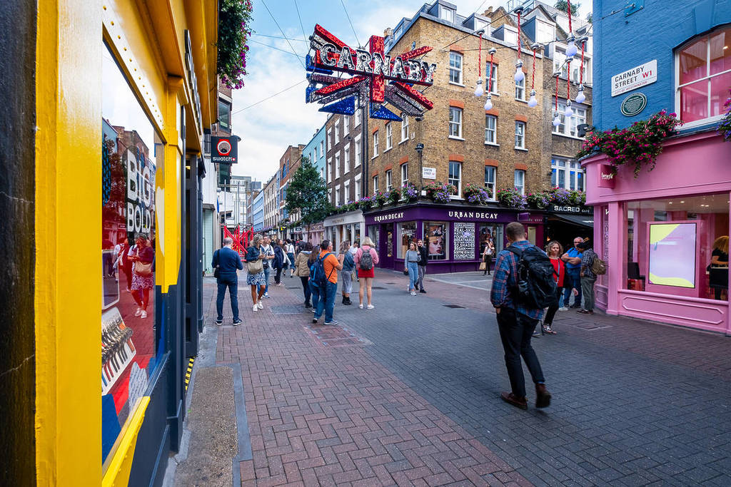 people milling about and walking on Carnaby street, a famous shopping street in Soho