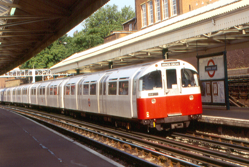 a vintage piccadilly line train travelling through a station, in an old photo