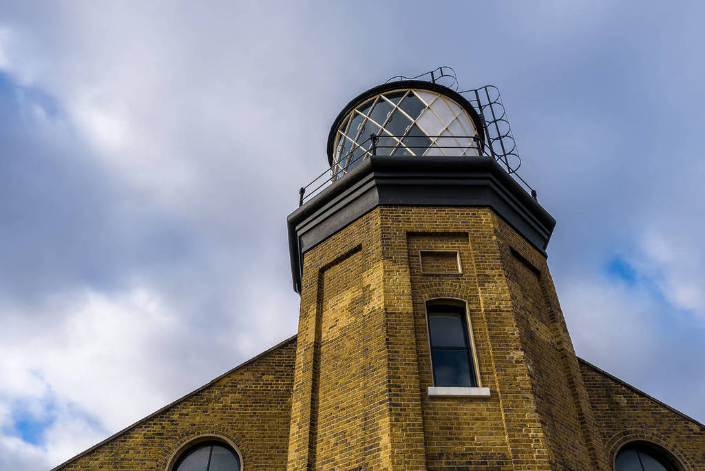 ein Leuchtturm, der aus der Spitze eines braunen Backsteingebäudes ragt
