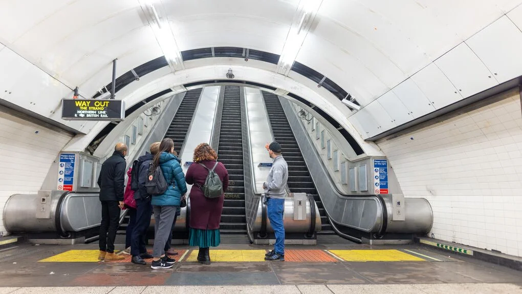 Des gens se tenaient au pied d’un escalator dans le métro londonien