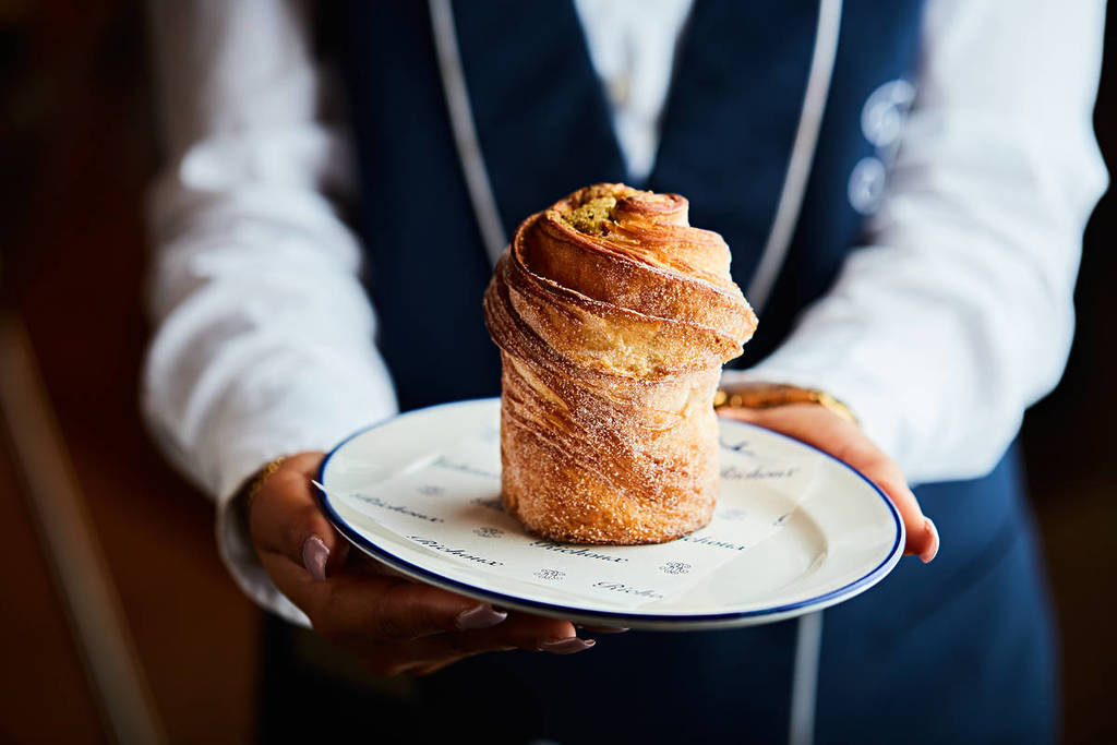 Ein Kellner hält einen Teller mit einem Cruffin hin