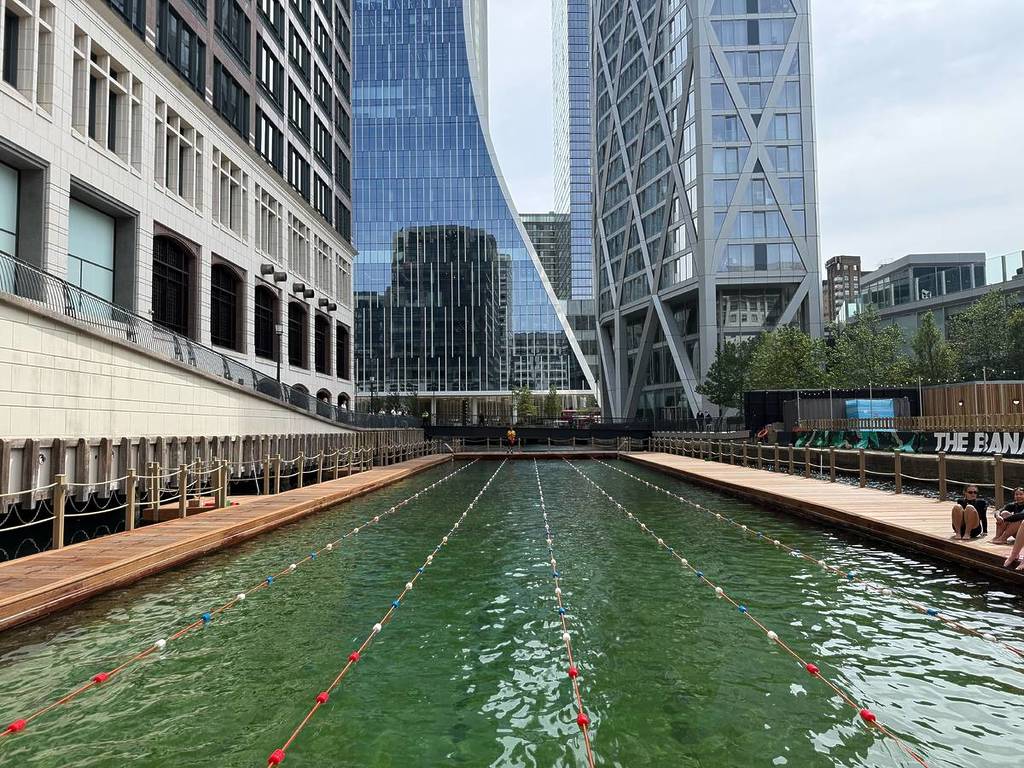 unas vistas desde el borde de la piscina de una piscina al aire libre flotante en Canary Wharf, con rascacielos elevándose a su alrededor