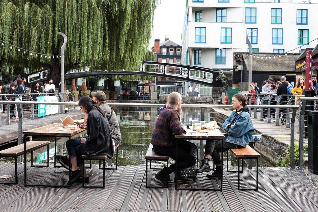 Menschen saßen auf Bänken neben dem Kanal am Camden Market