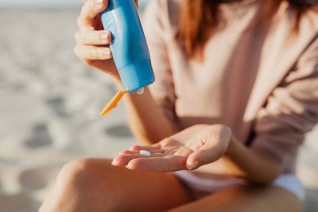 Iemand smeert zich in met zonnebrandcrème op het strand op een zonnige dag.
