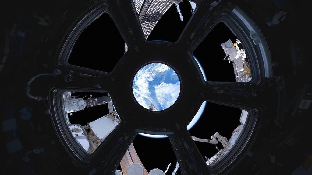 une vue de la Terre à travers une fenêtre circulaire en forme de moulin à vent sur la Station spatiale internationale