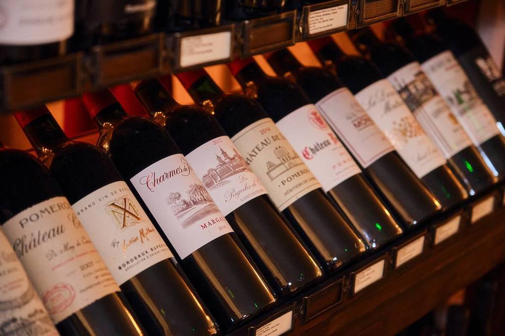 Uma fila de garrafas de vinho tinto com vários rótulos