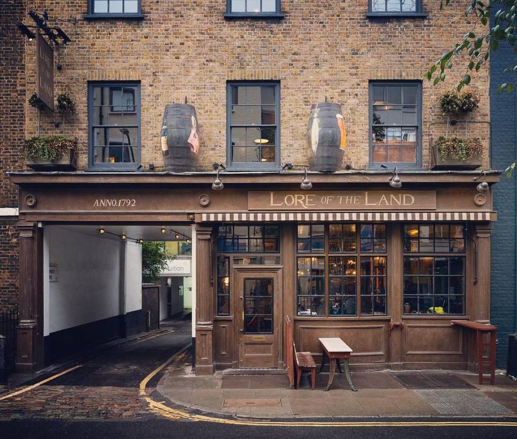 Das Äußere eines Pubs in Fitzrovia mit Holzbänken draußen
