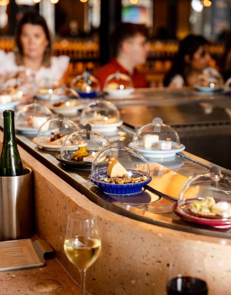 a conveyor belt of plates of cheese travelling through the pick & cheese restaurant