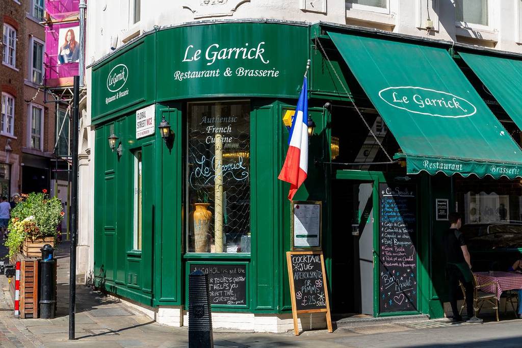 Die Außenseite des Restaurants Le Garrick mit einer französischen Flagge draußen und einer dunkelgrünen Fassade