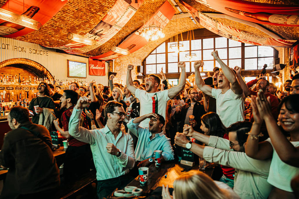 Eine Menschenmenge, hauptsächlich Männer, jubelt während einer Football-Watch-Party am Flat Iron Square