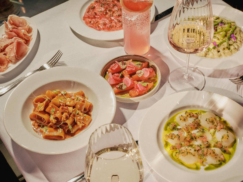 un tavolo imbandito con piatti estivi, bicchieri di vino e cocktail