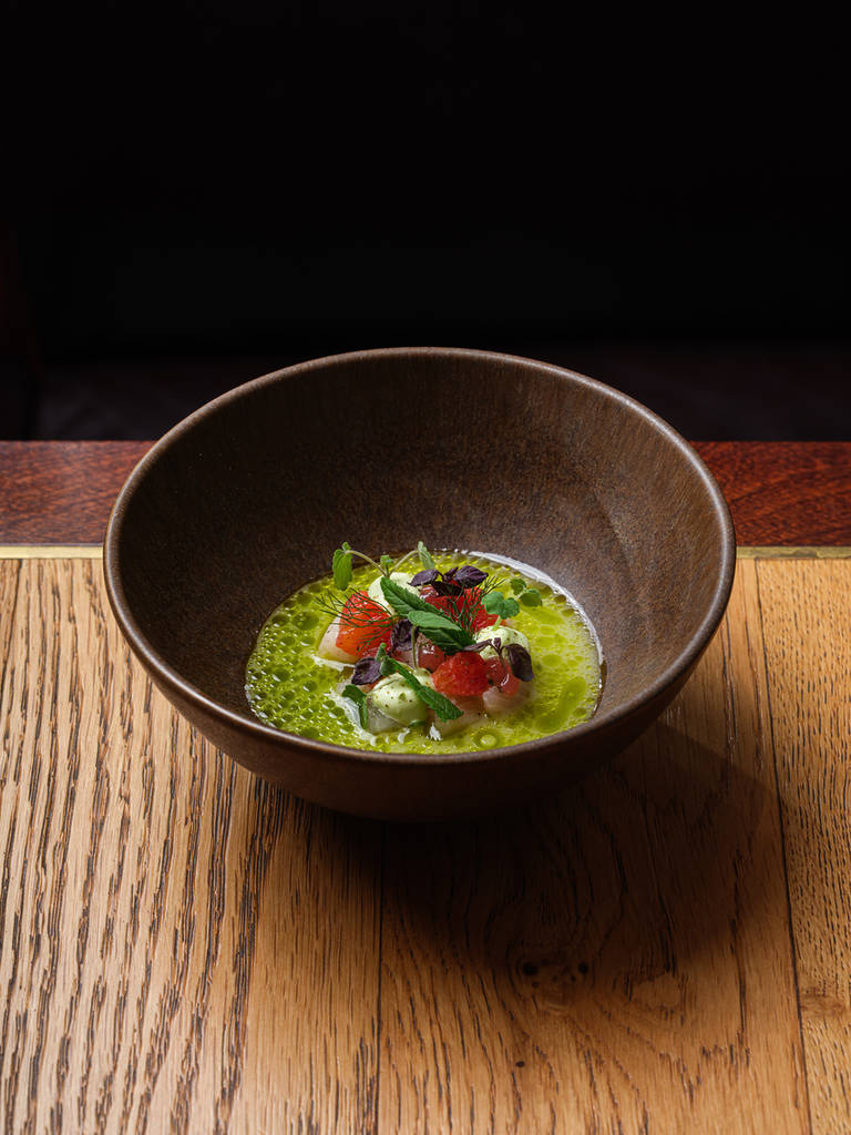 une sauce vert vif sur un plat de poisson cru et de fraises
