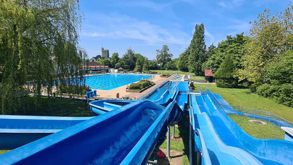 Der Blick von oben auf eine Wasserrutsche mit einem großen Swimmingpool, der unten von angelegten Gärten umgeben ist