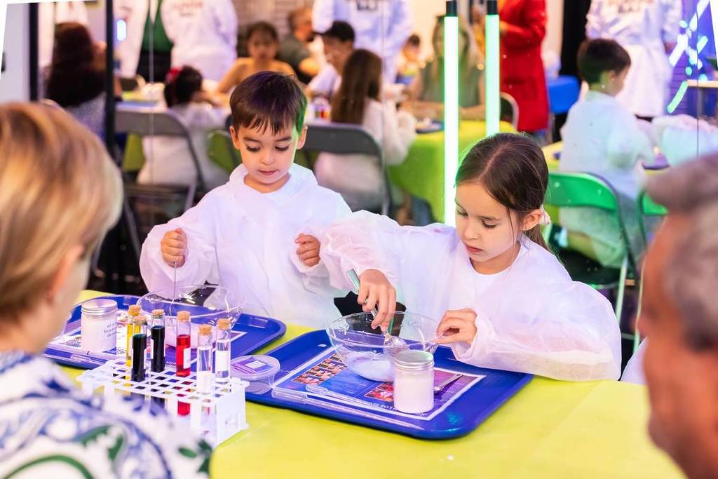 Zwei Kinder führen gemeinsam mit ihren Eltern ein Experiment im Mini Genius Lab durch