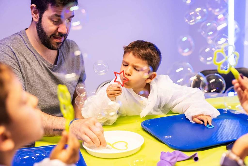 Ein kleines Kind, das mit seinem Vater Seifenblasen zerplatzt