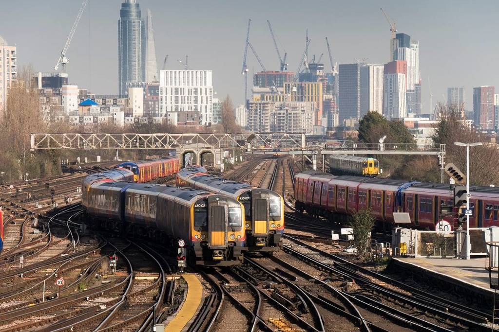 Züge nähern sich dem Bahnhof Clapham Junction mit der Skyline von London im Hintergrund
