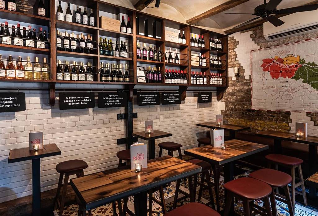 Tische in einer Weinbar mit Regalen voller Weinflaschen an der Wand