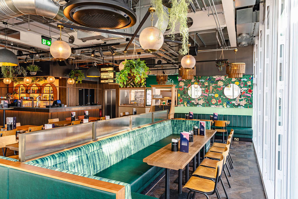 la zona de asientos del mercado gastronómico, con cómodas cabinas, y un bar al fondo