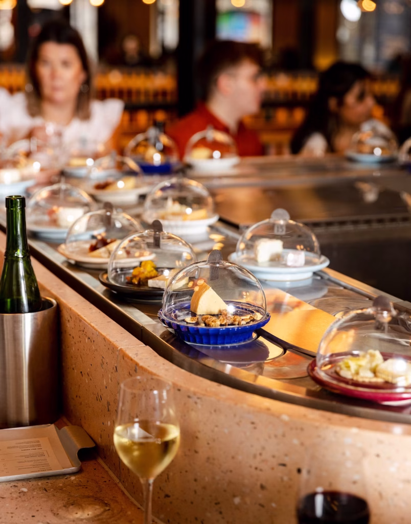 un nastro trasportatore con piatti di formaggio che attraversa il ristorante Pick & Cheese