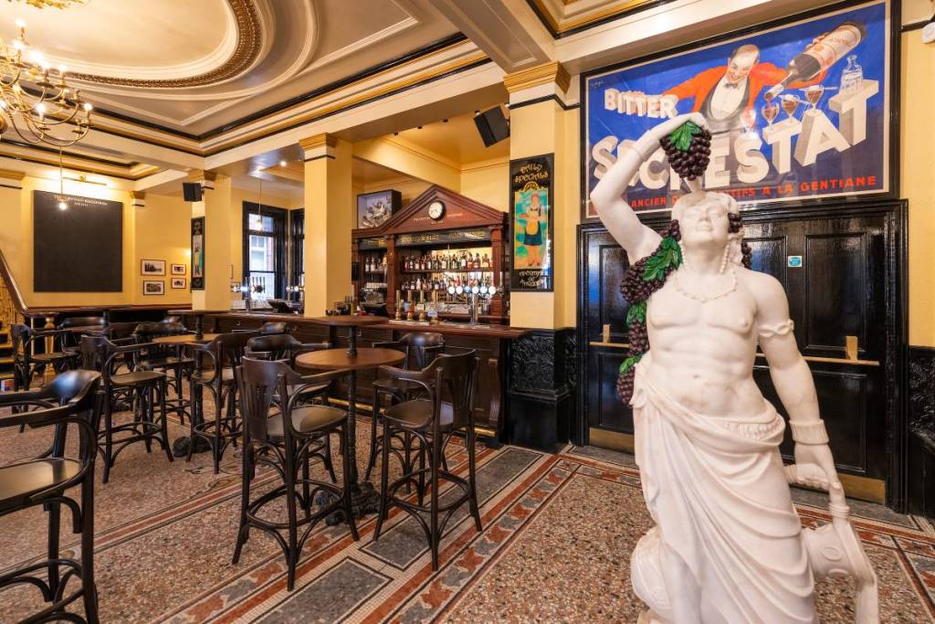 Das Interieur einer Kneipe mit Tischen, Barhockern und einer Statue
