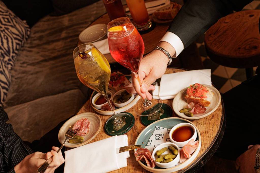 une table garnie d’une sélection de charcuterie et d’en-cas, ainsi que deux cocktails spritz