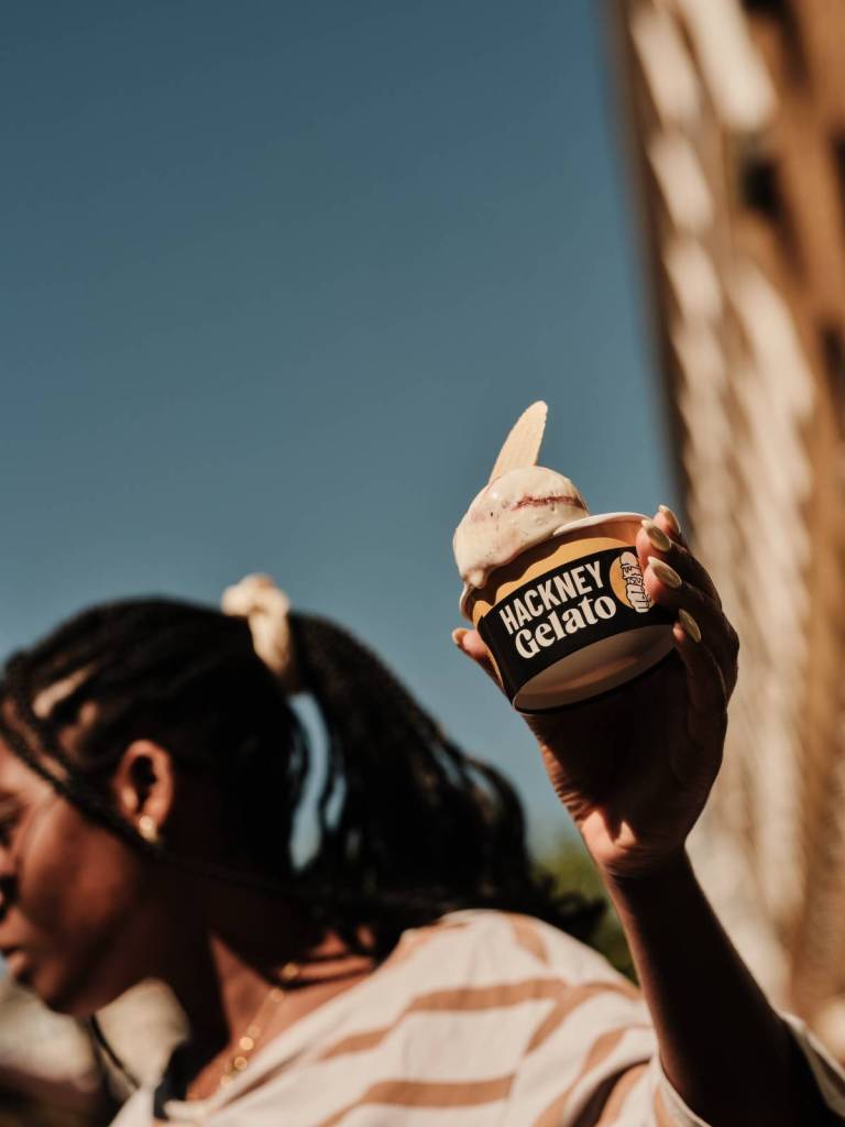 iemand die een ‘Hackney Gelato’-beker vasthoudt met wat gelato erin