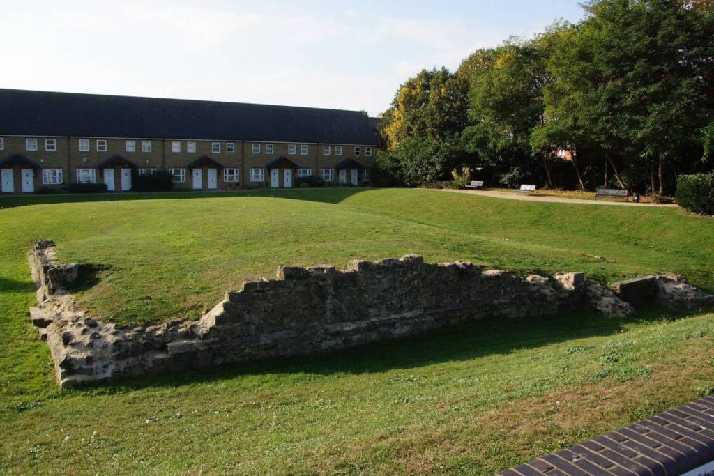 las ruinas de una muralla medieval visibles en un campo cubierto de hierba